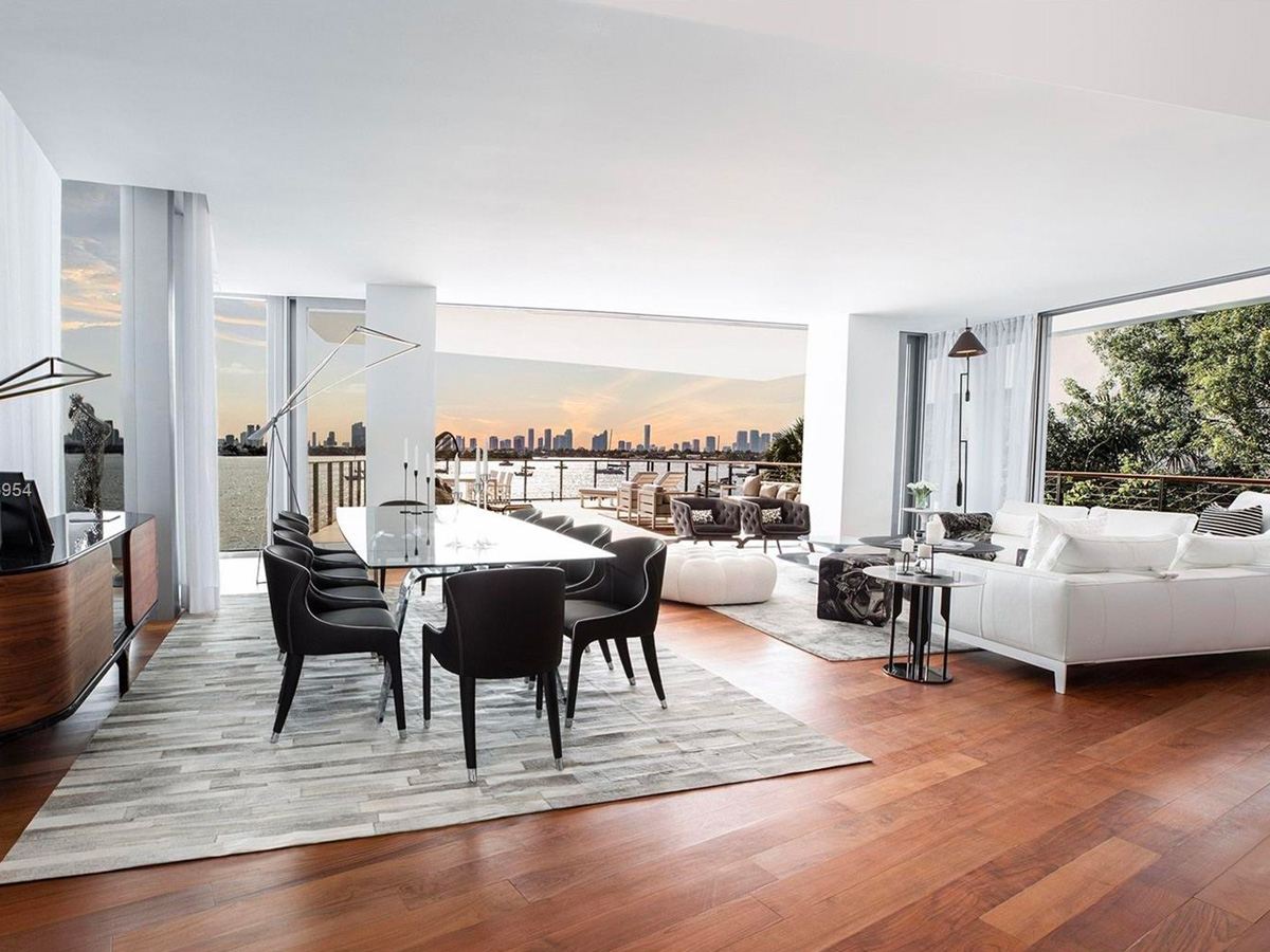 inside dining room at Monad Terrace residences featuring large white table with black chairs with surrounding couches surrounded by large glass windows.