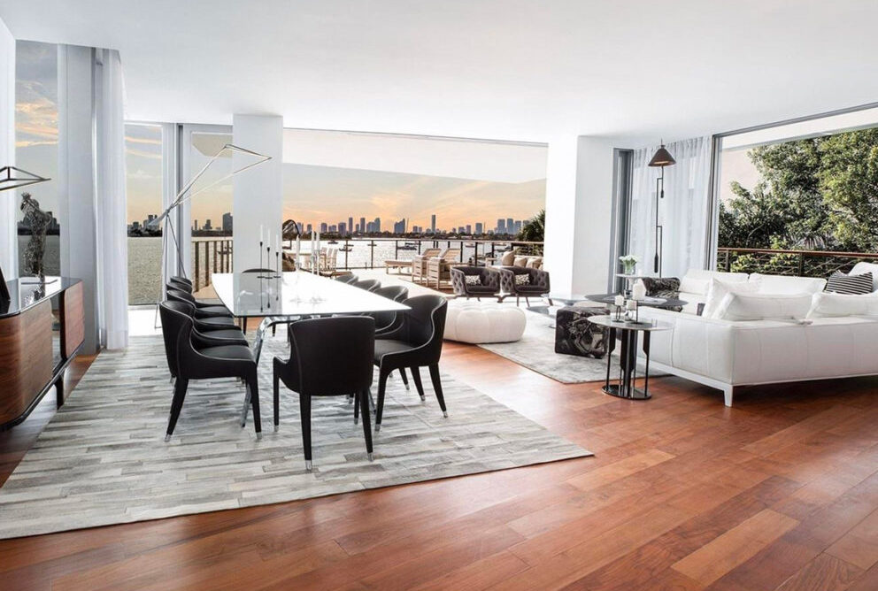 inside dining room at Monad Terrace residences featuring large white table with black chairs with surrounding couches surrounded by large glass windows.